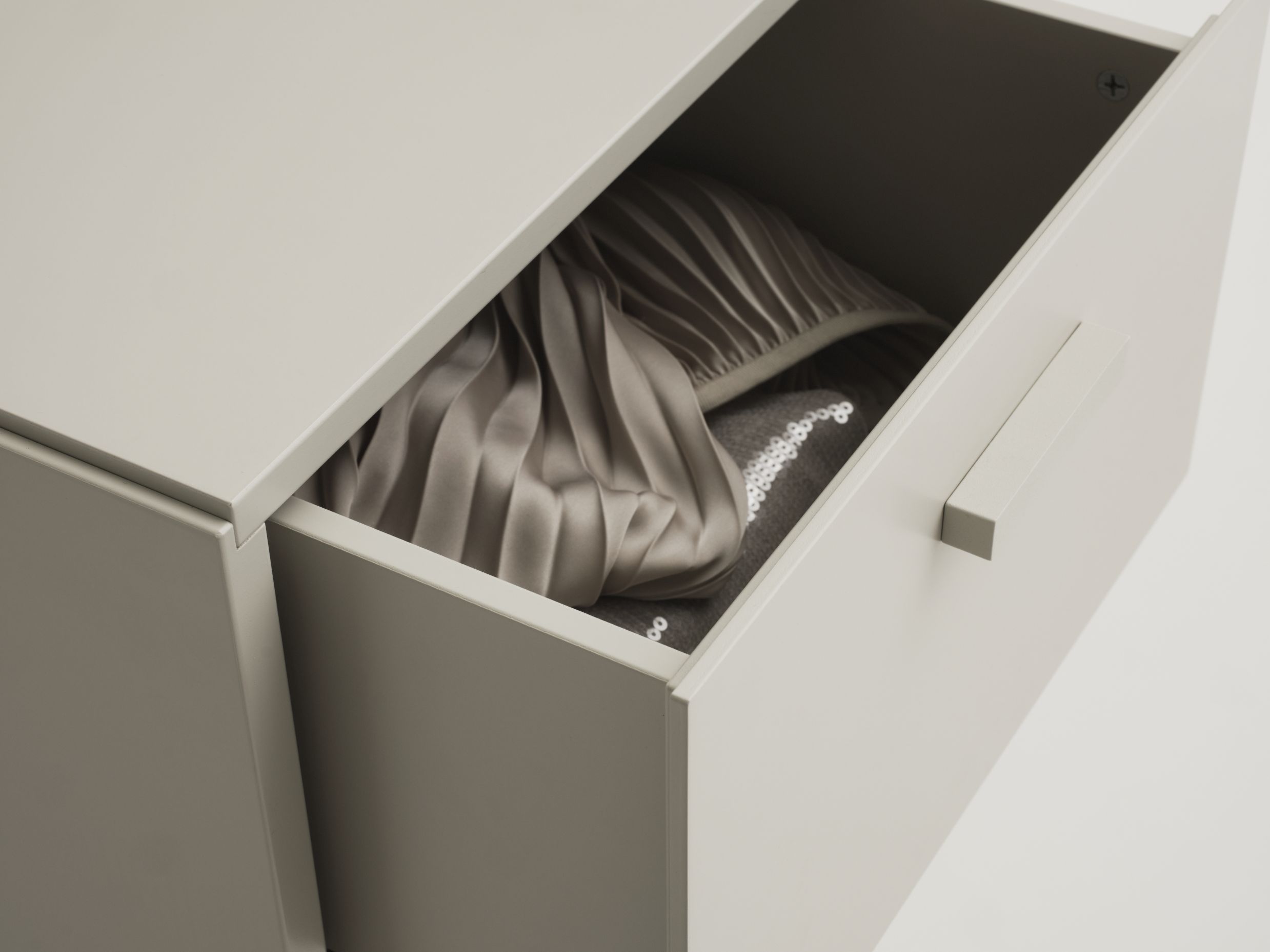 Geöffnete Schublade einer Relief Kommode von String Furniture mit Textilien. Möbel für Schlafzimmer und Wohnzimmer.