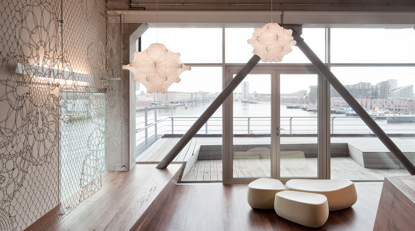 Zwei moderne Taraxacum Hängeleuchten von Flos in einem hellen, offenen Wohnraum mit Wasserblick.