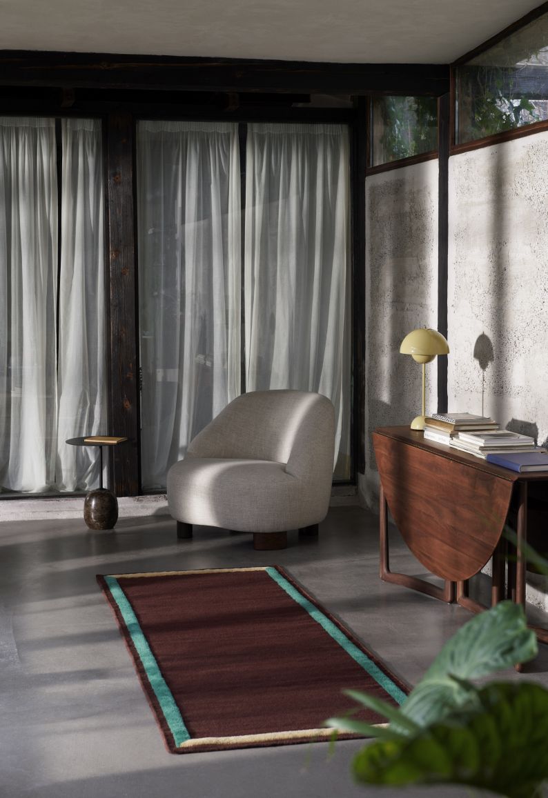 AndTradition Margas Loungesessel LC1 in hellem Stoffbezug, kombiniert mit Beistelltisch und Teppich.