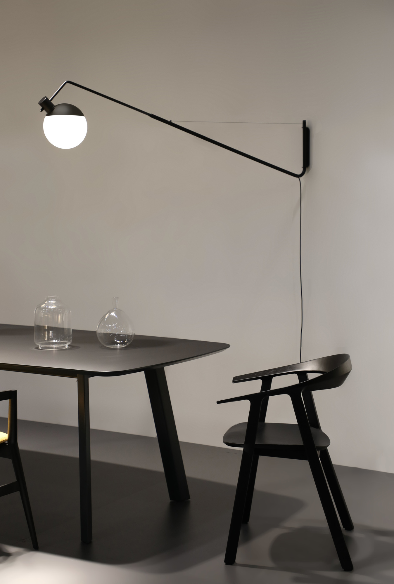 Schwarze Baluna Wandleuchte von Grupa über Esstisch mit Stuhl. Moderne Innenbeleuchtung für Wohnzimmer.