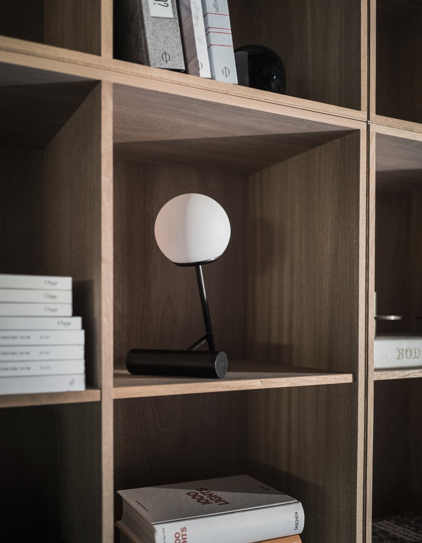 Nahaufnahme der schwarzen Audo Phare LED Tischleuchte mit weißem Lampenschirm im Regal.
