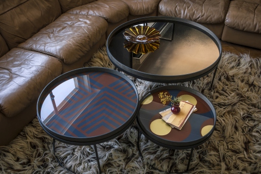 Ansicht von drei runden Ethnicraft Beistelltischen mit verschiedenen Mustern und Oberflächen im Wohnzimmer.