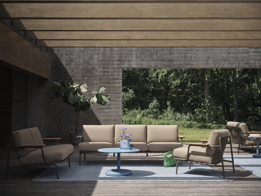 Muuto Settle 3-Sitzer Outdoor Sofa in Beige auf Terrasse mit Sessel und Tisch.