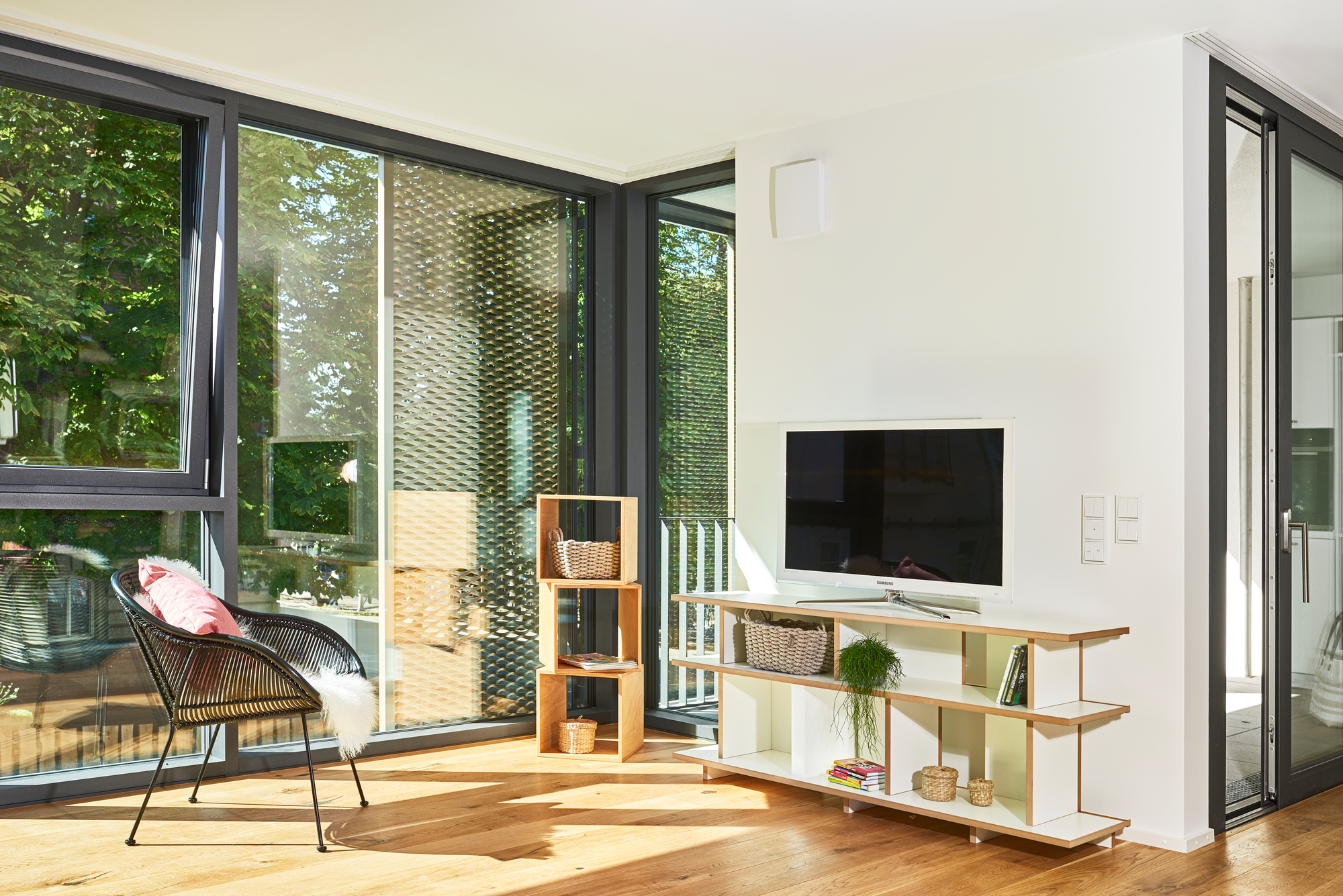 Wohnzimmer mit niedrigem Tojo Stell Regal Anbaumodul aus Holz, kombiniert mit weißem TV-Lowboard.