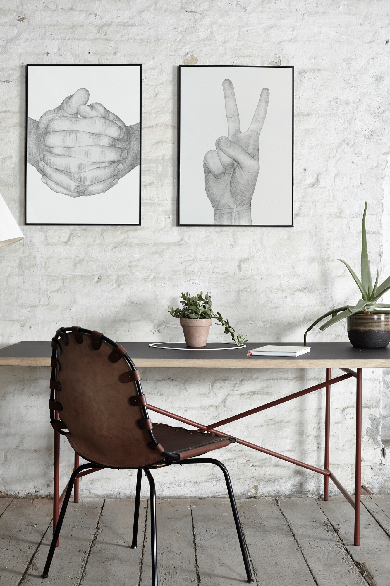 Nahaufnahme des Folded Hands Poster von Paper Collective, gerahmte Kunstdrucke an weißer Ziegelwand.