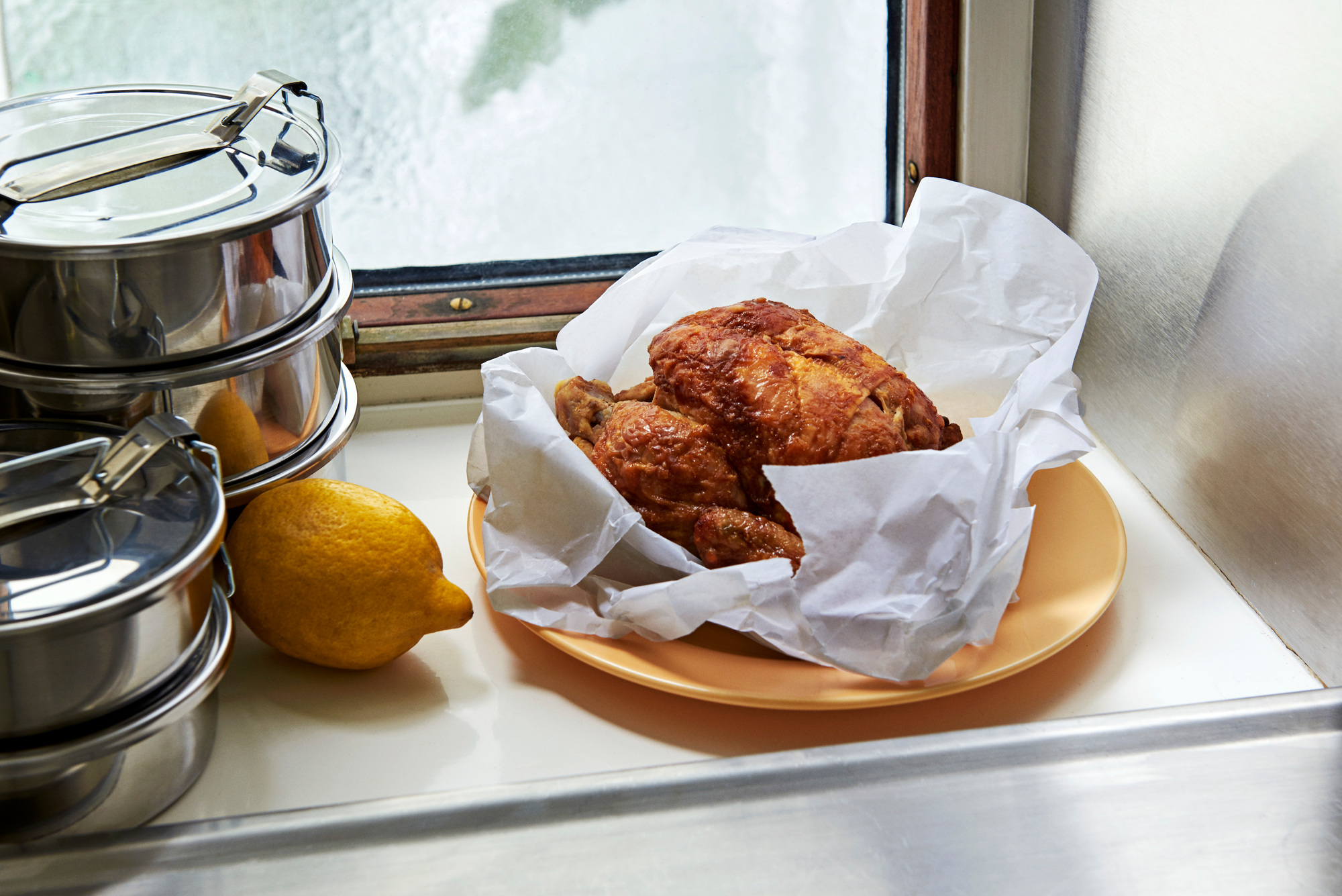 Stapelbare runde Steel Lunch Box Brotdosen aus Edelstahl neben Zitrone und Brathähnchen.