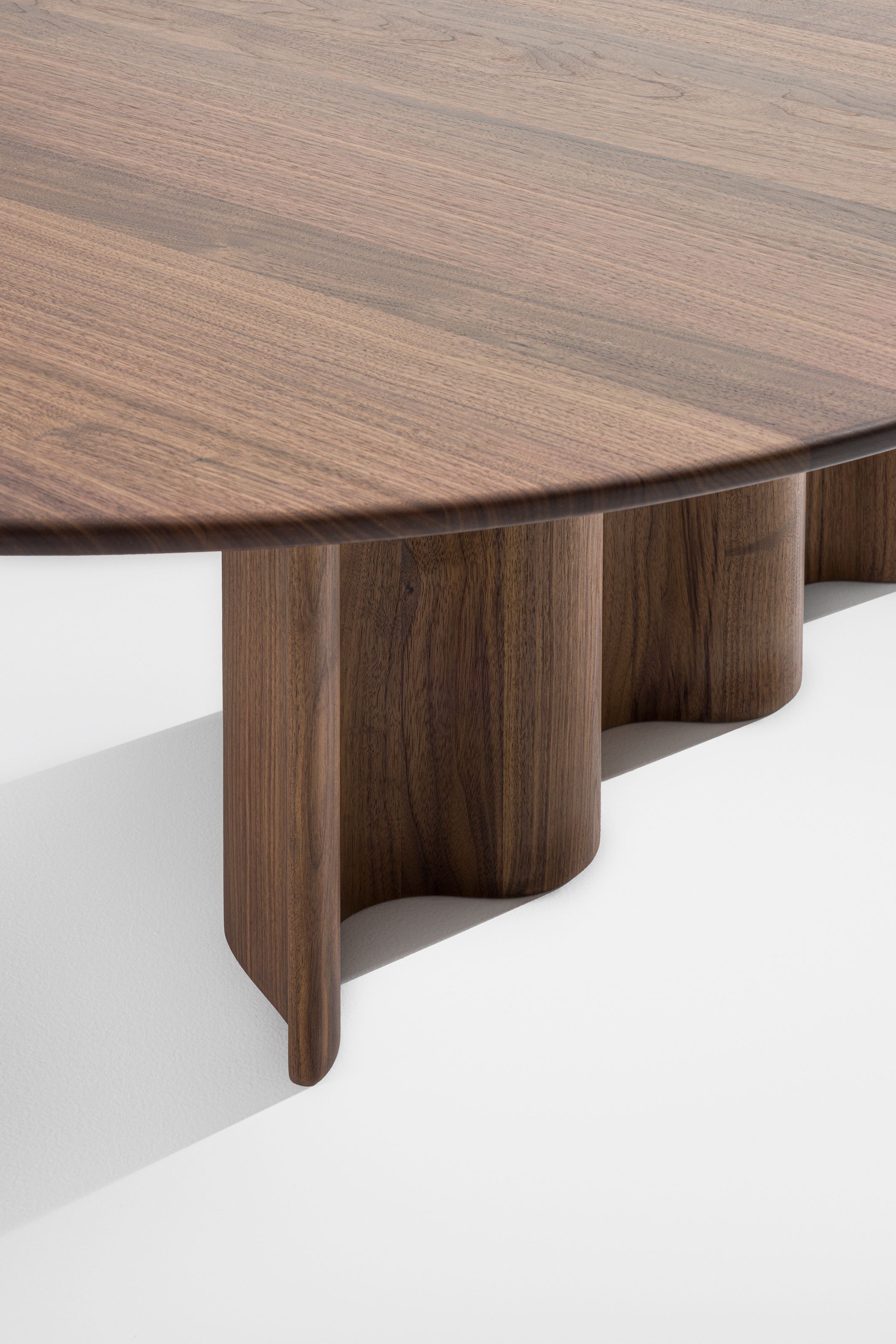 Detailaufnahme eines runden Couchtisches aus Walnussholz mit einzigartigem, geschwungenem Untergestell.