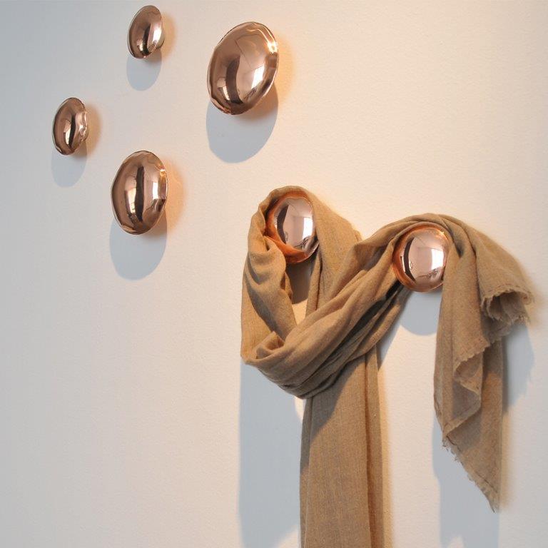 Wand mit fünf Pins Garderobenhaken in Kupferoptik, zwei davon mit beigem Schal.