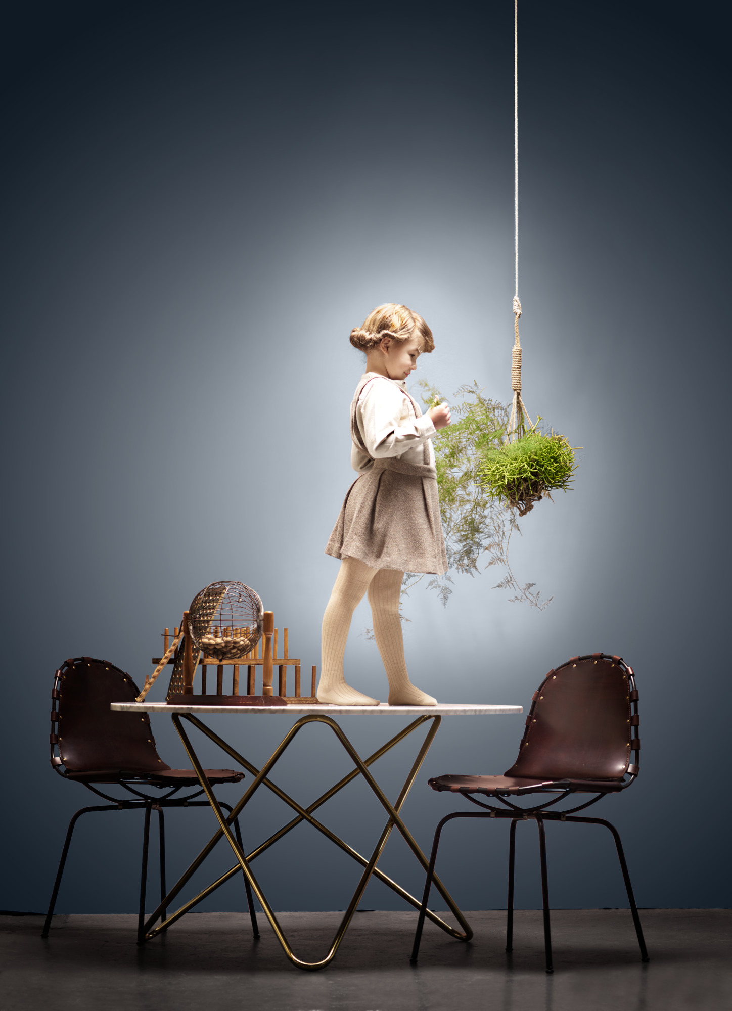 Big O Tisch von Ox Denmarq: Marmortisch mit goldenem Gestell und Kind.