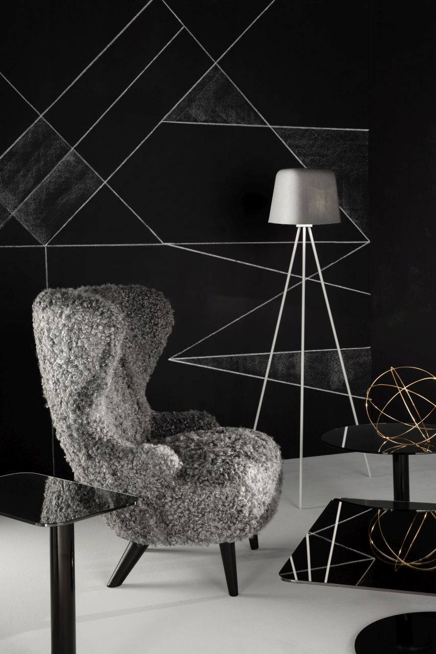 Schwarzer Flash Beistelltisch von Tom Dixon neben Sessel und Lampe in modernem Wohnzimmer.