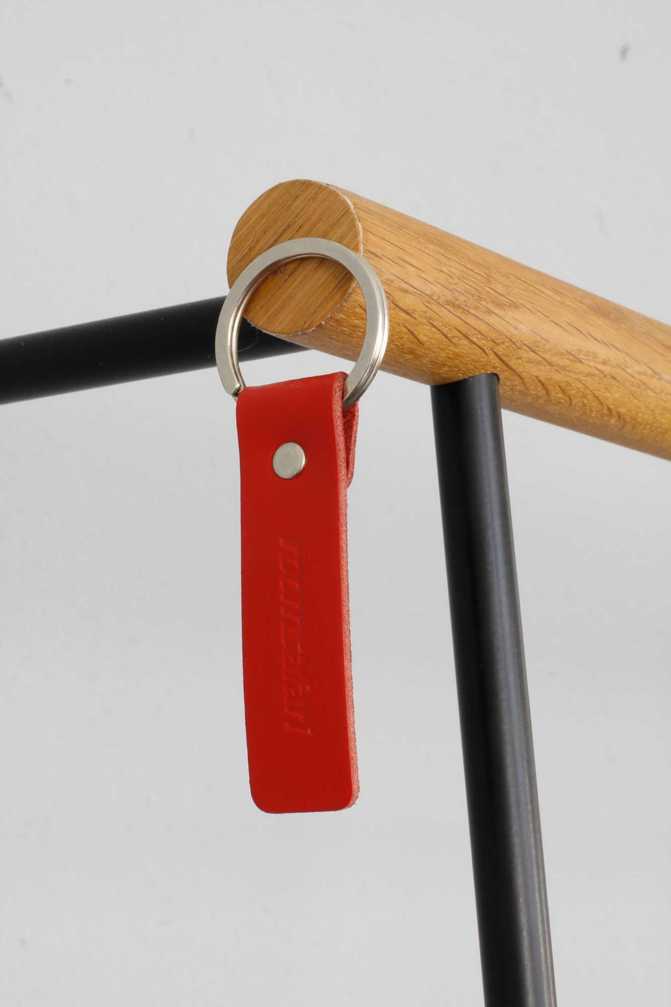 Detailaufnahme der Leanon II Anlehngarderobe von Roomsafari, schwarze Säule mit rotem Schlüsselanhänger.