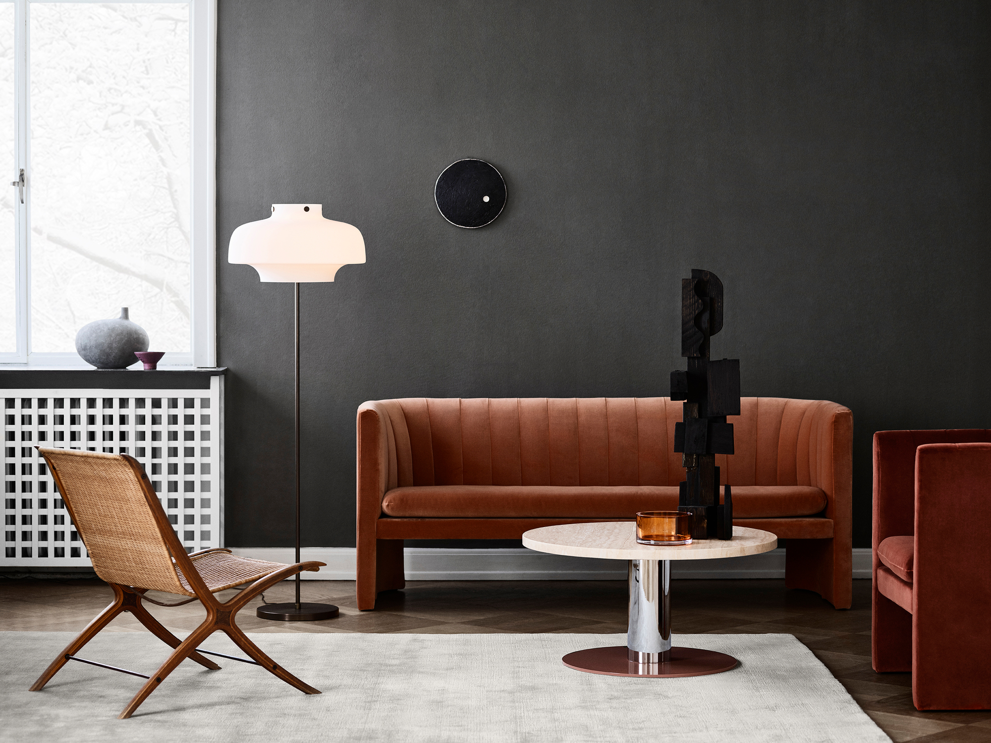 Wohnzimmer-Szene mit Loafer Sofa von AndTradition, Sessel, Tisch und Design-Elementen in warmen Farben.