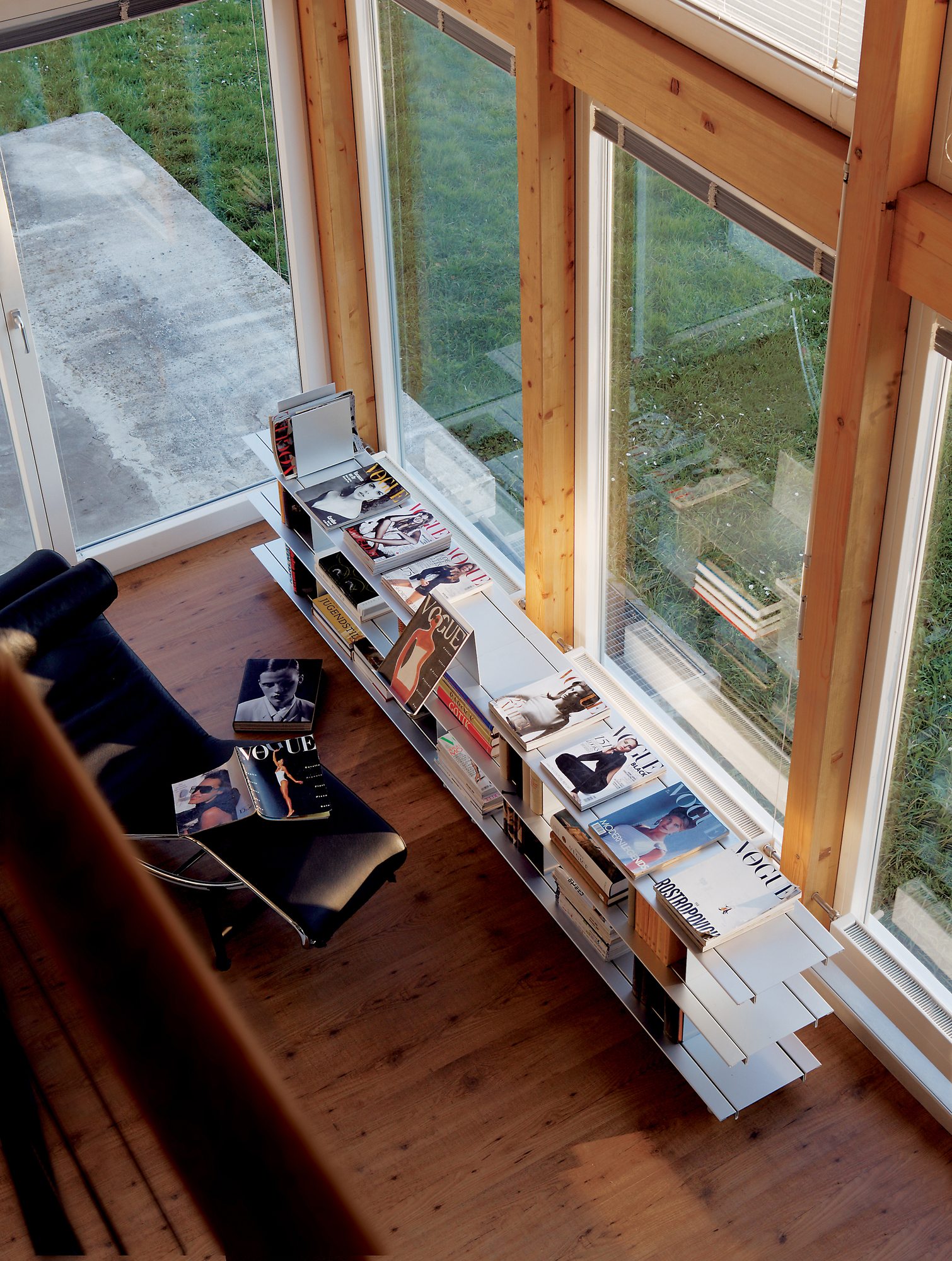 Helles Zimmer mit Zoll D Regal von Nils Holger Moormann, gefüllt mit Büchern und Magazinen.