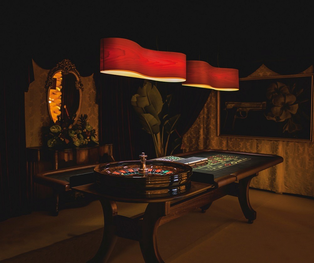 Zwei rote New Wave Pendelleuchten von LZF Lamps über einem Roulettetisch in dunklem Ambiente.