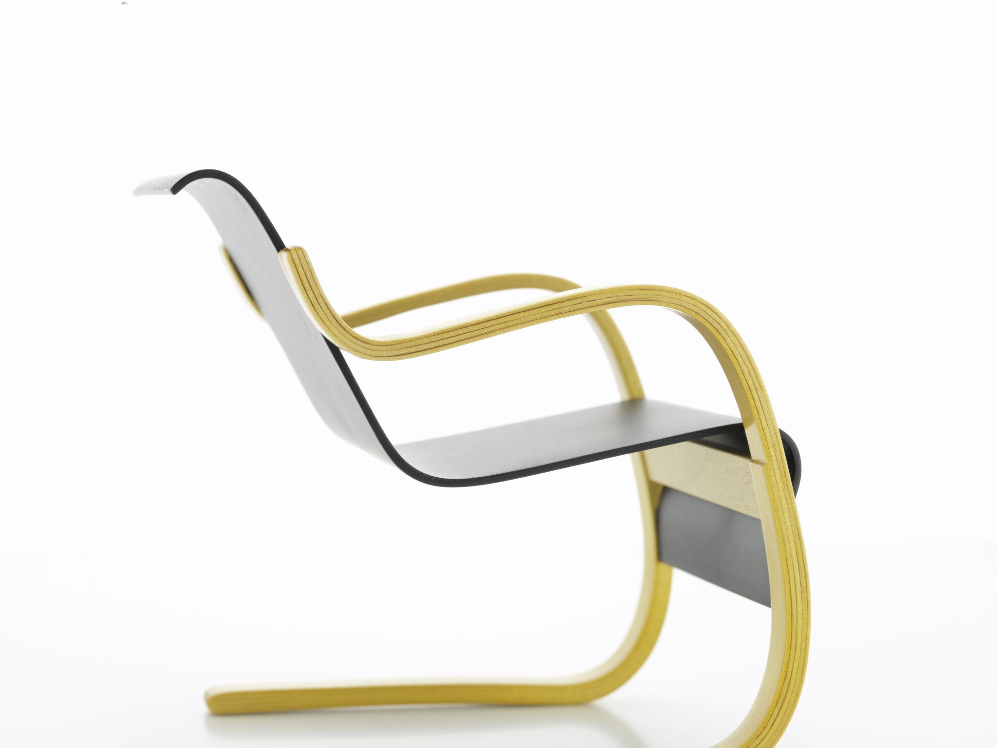 Detailaufnahme: Armchair Nr. 42 Miniatur Sessel von Vitra mit hellem Holzrahmen und schwarzer Sitzfläche.