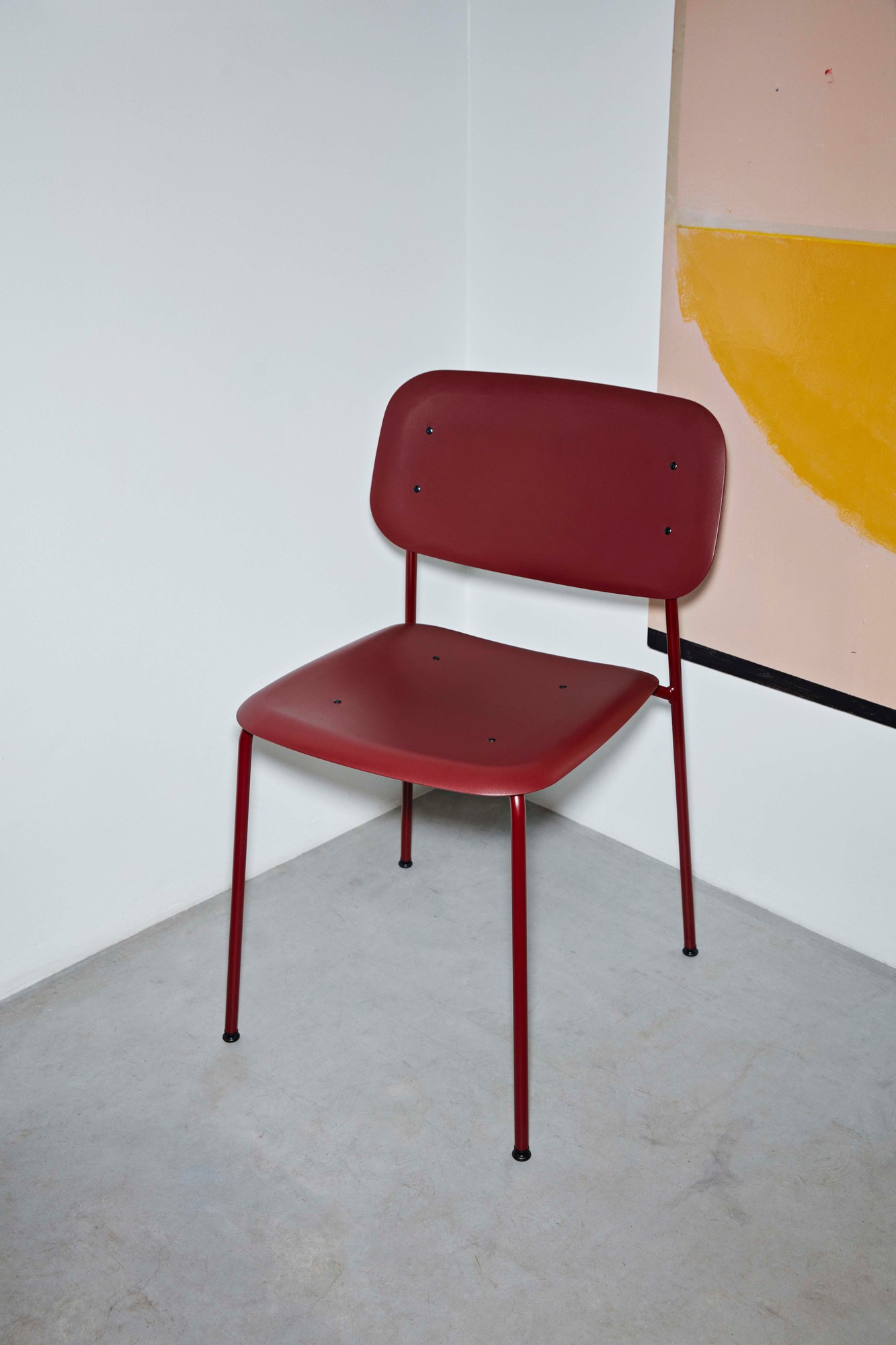 Burgunderroter Hay Stuhl Soft Edge 45 Chair mit Stahlgestell vor weißer Wand.