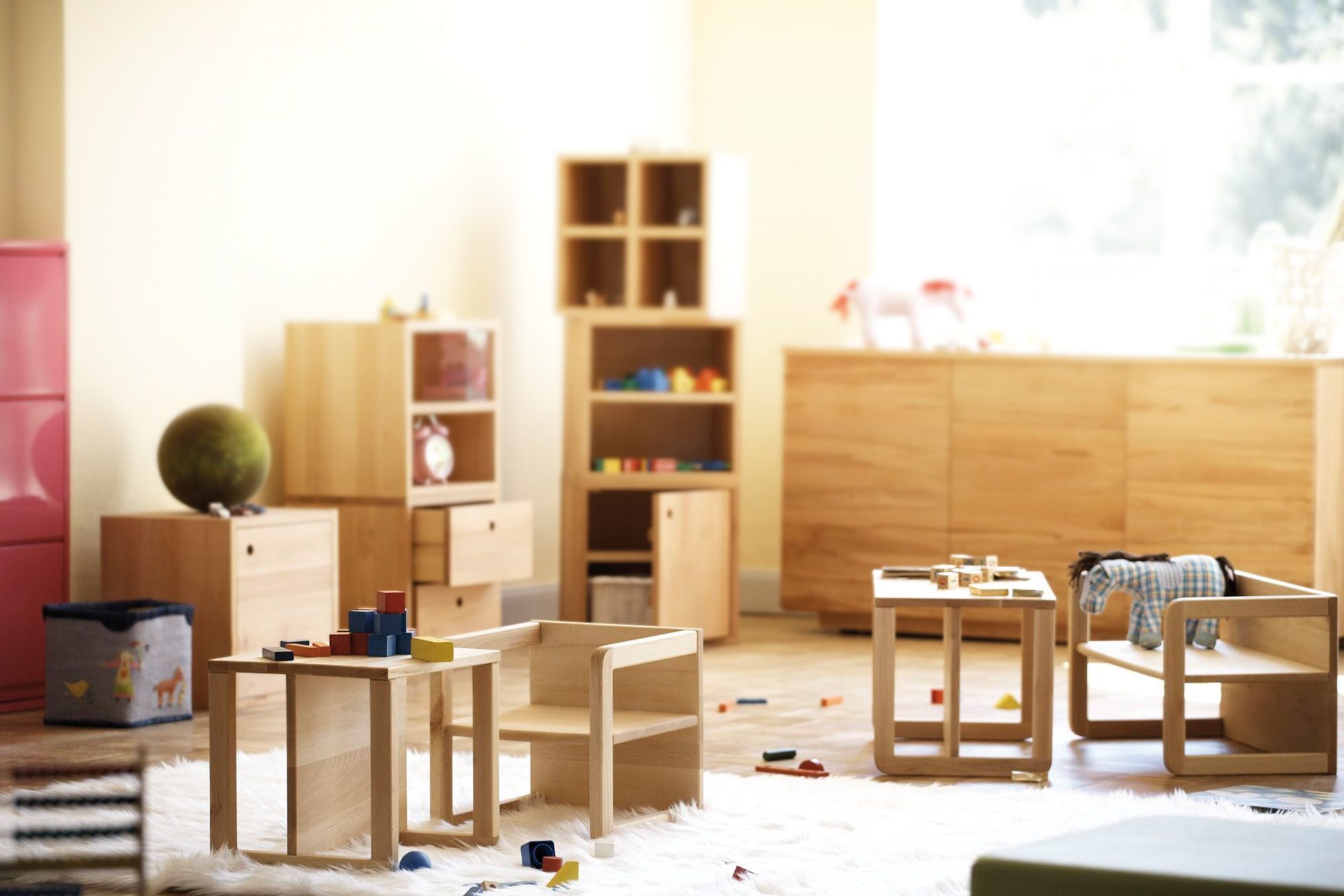 Helles Kinderzimmer mit Tim Kindertisch und Kinderbank aus Holz von Jan Kurtz, mit Spielsachen dekoriert.