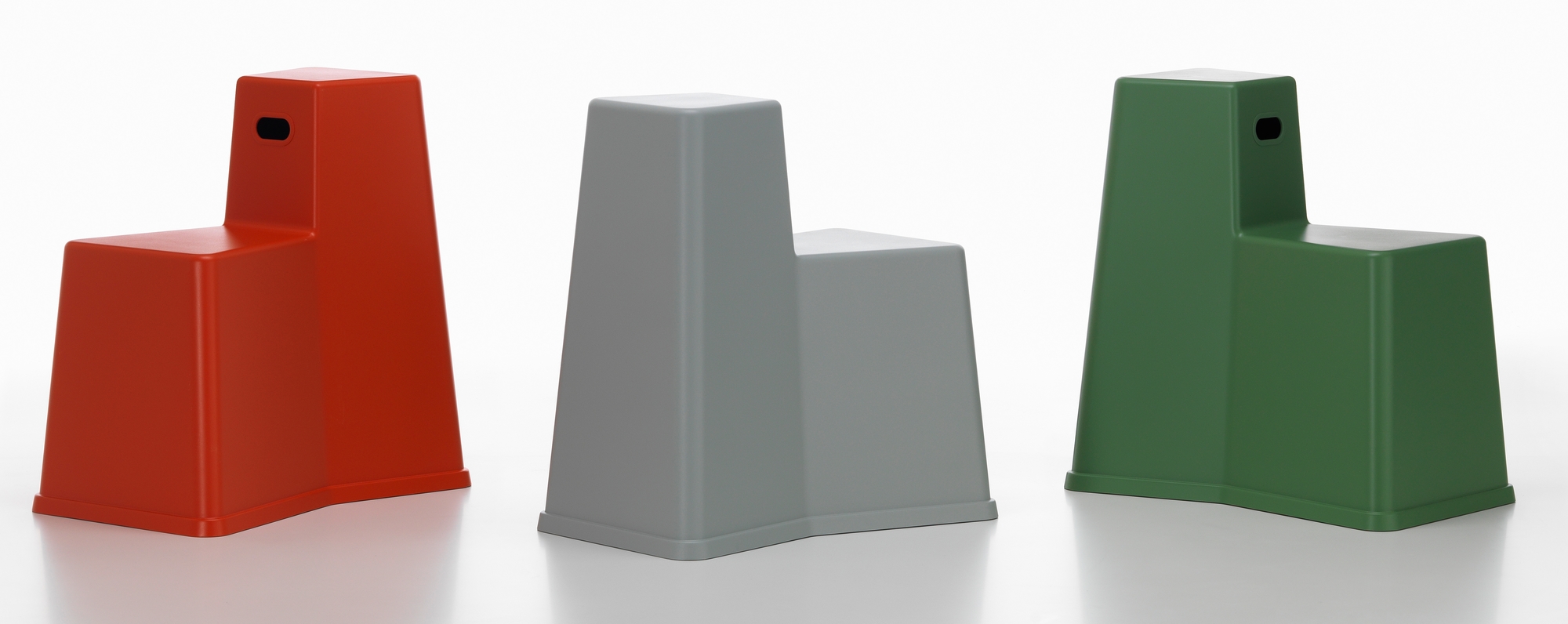Drei Vitra Stool Tool Hocker in Rot, Grau und Grün, modernes Design.