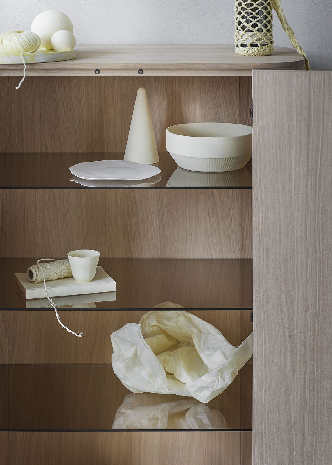 Detailaufnahme: Loud Schrank aus geräucherter Eiche mit Glasböden und dekorativen Objekten.