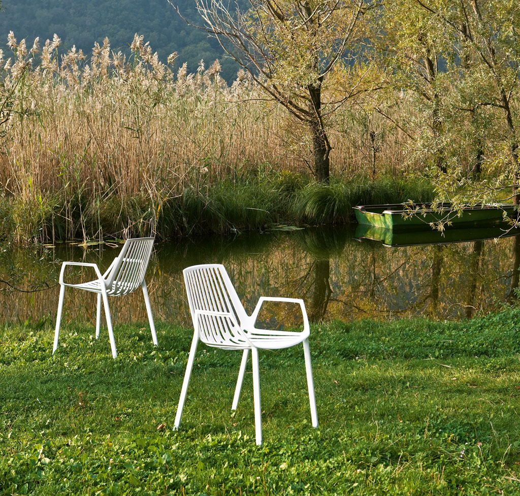 Zwei weiße Rion Outdoor Sessel vor einem See. Gartenmöbel, Sitzmöbel für Terrasse und Balkon.