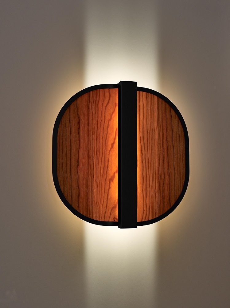Nahaufnahme der beleuchteten Omma Wandleuchte von LZF Lamps mit Holzfurnier und schwarzem Rahmen.
