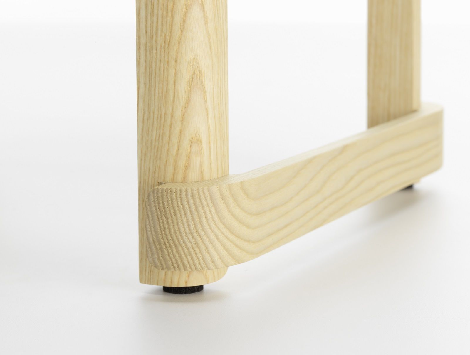 Detailaufnahme: Bein und Fußstütze des Atelier Bar Stool Barhockers von Artek aus hellem Holz.