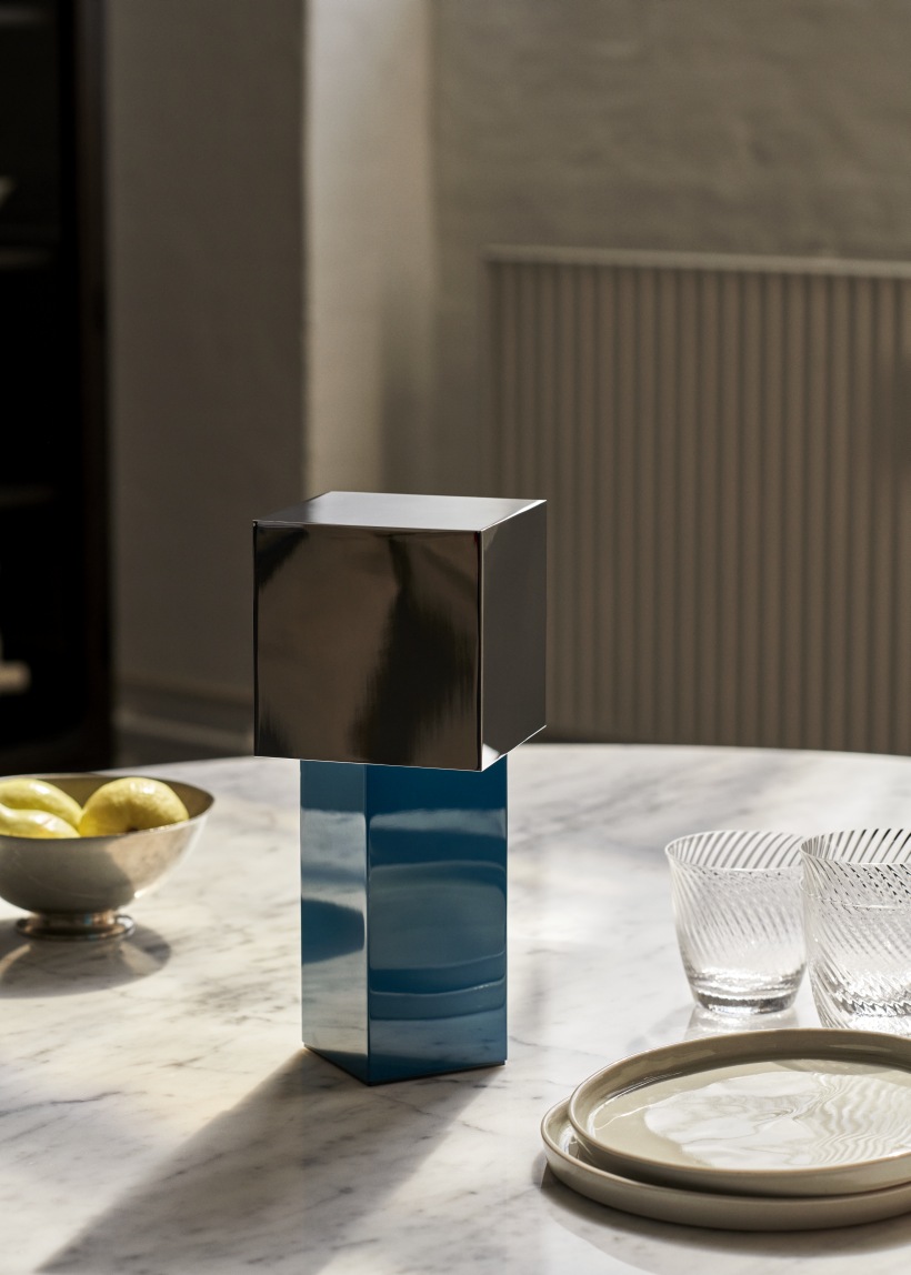 AndTradition Pivot ATD7 Tischleuchte, blaue Akkuleuchte mit schwarzem Lampenschirm auf einem Tisch.