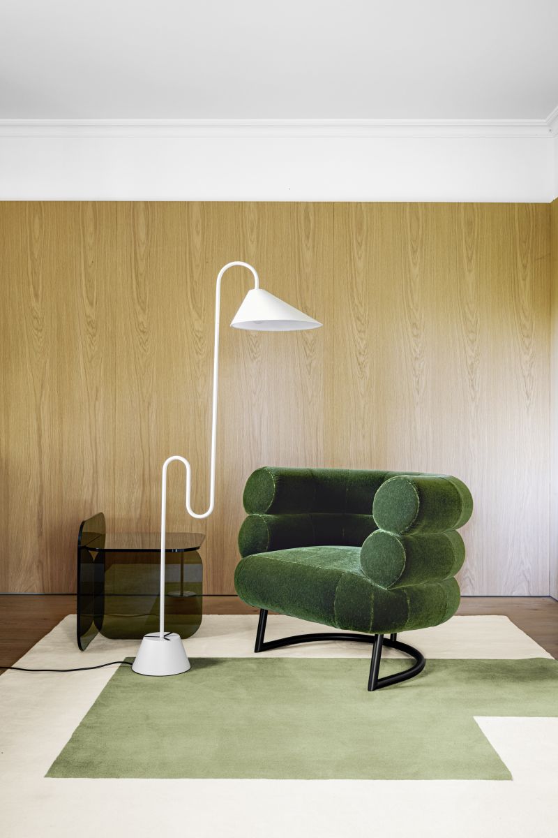 Weiße Roattino Stehleuchte von ClassiCon neben grünem Sessel und Beistelltisch auf Teppich.