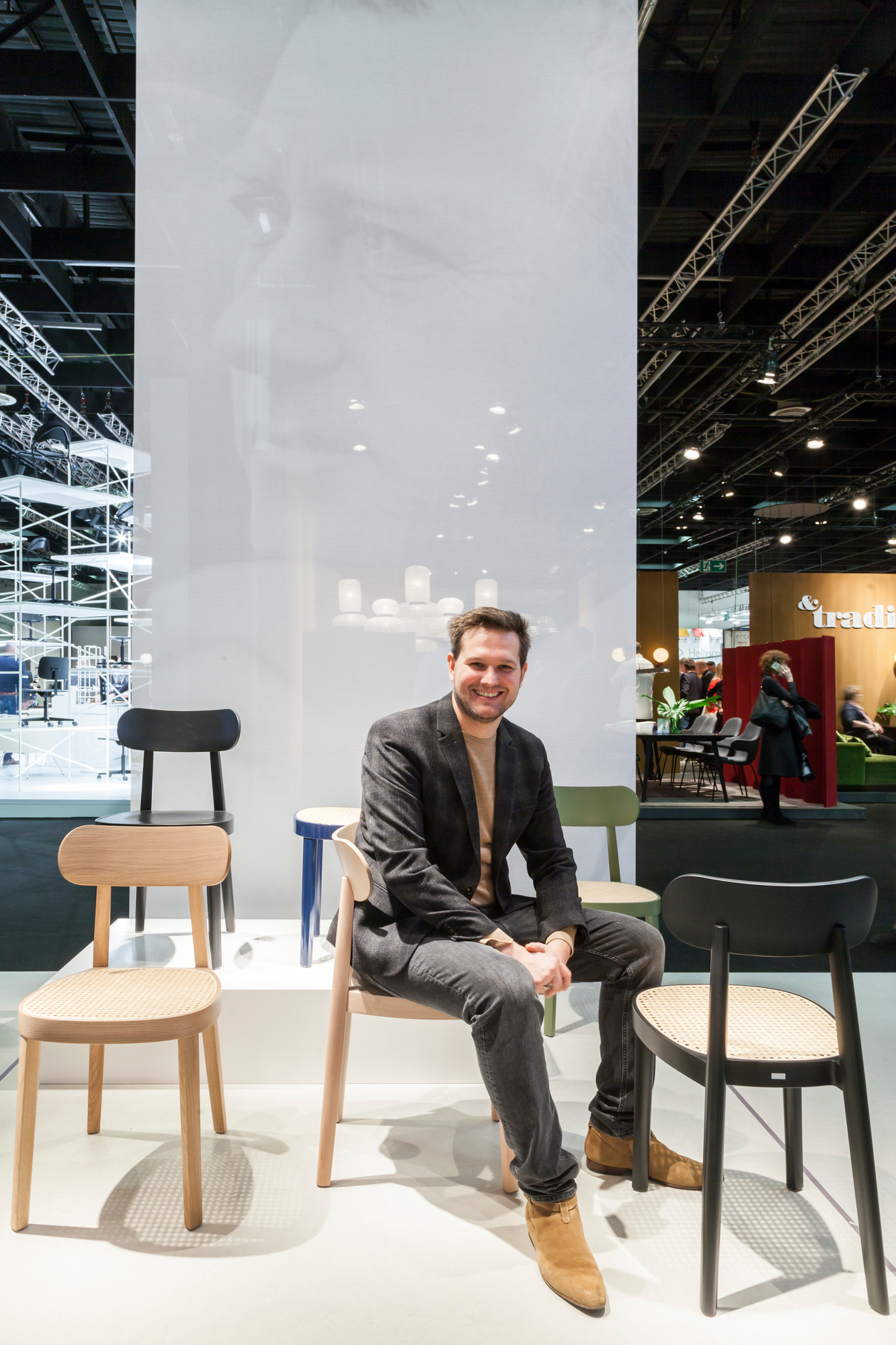 Mann sitzt auf einem hellen Holzstuhl, Thonet 118 M ähnlich, mit Wiener Geflecht.