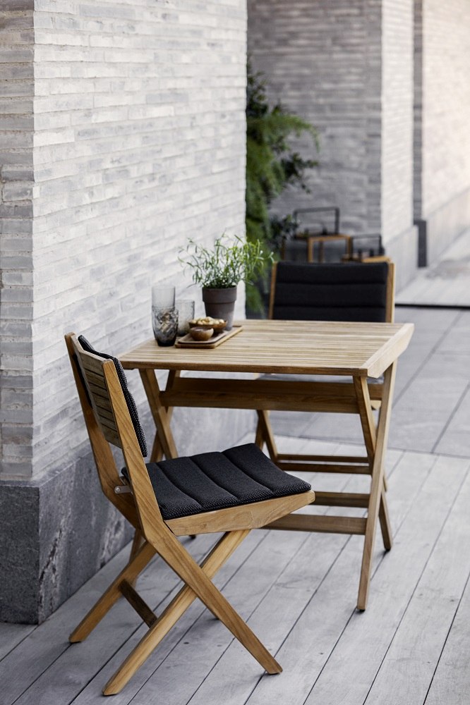 Cane-Line Flip Outdoor Stuhl mit dunkelgrauem Sitz- und Rückenkissen für bequemes Sitzen im Freien.