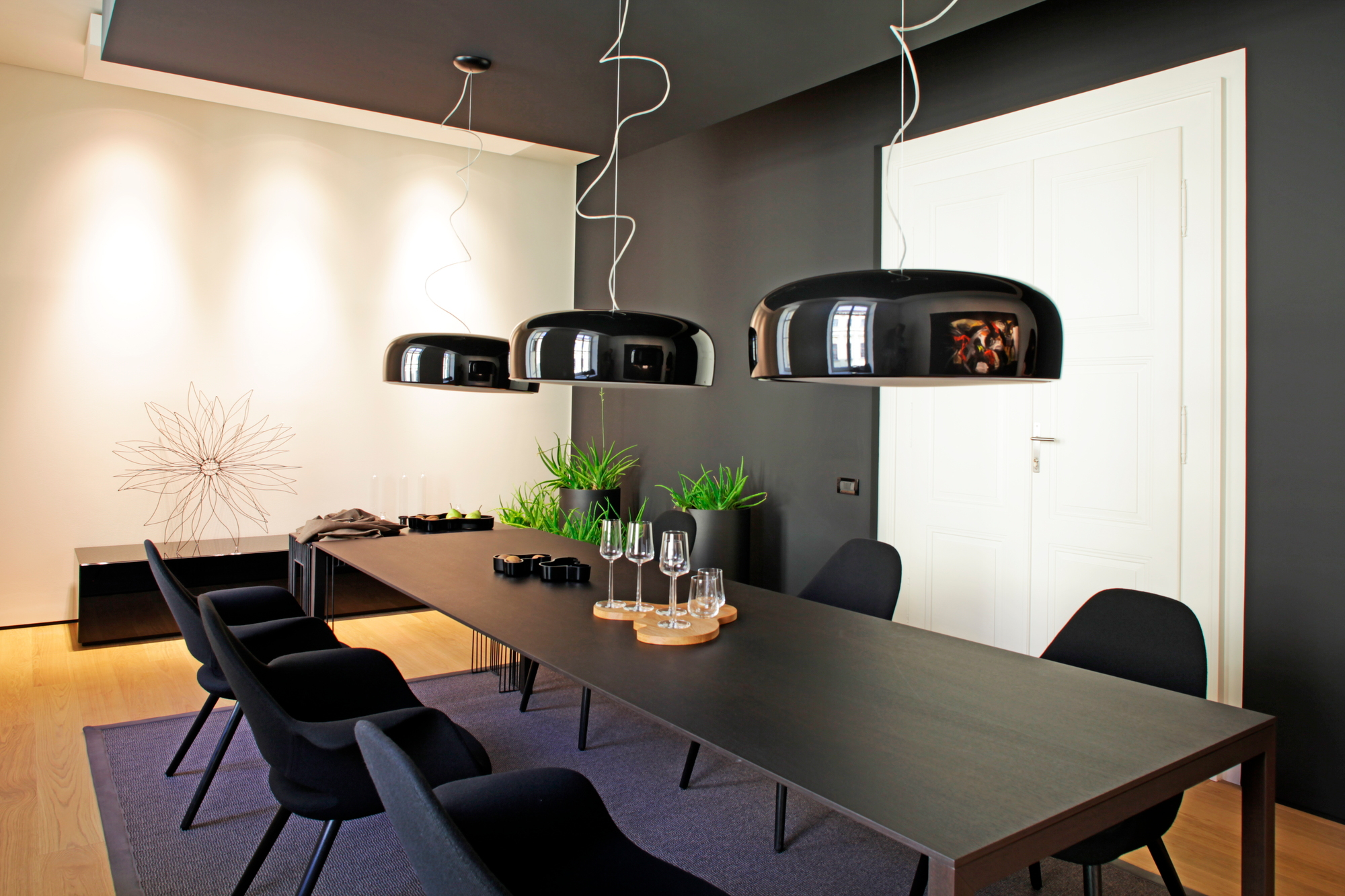 Esszimmer mit schwarzem Tisch, Stühlen und drei schwarzen Smithfield Pendelleuchten von Flos.