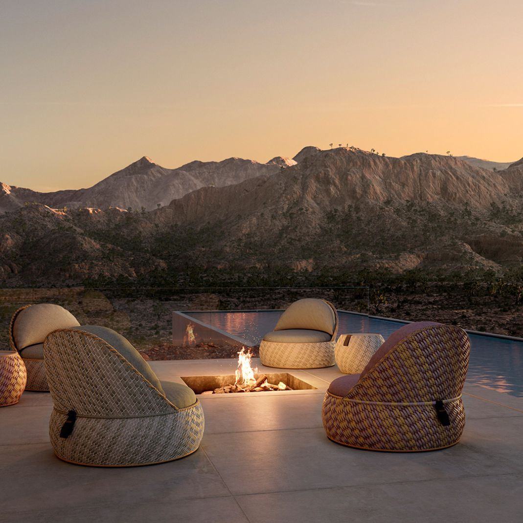 Outdoor-Lounge-Set mit Korbsesseln und Feuerstelle vor Bergkulisse für entspannte Abende im Freien.