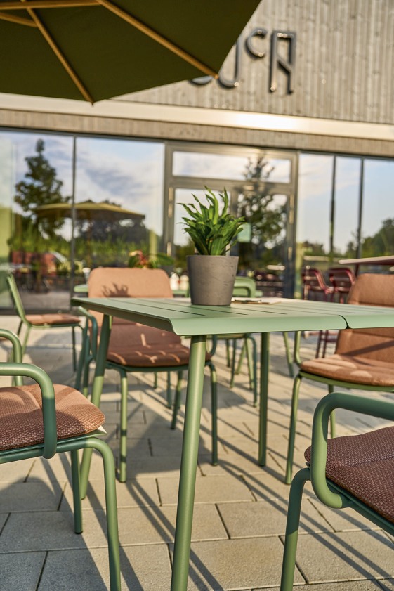 Weishäupl Vapio Sessel und Tisch für den Außenbereich in Grün mit braunen Sitzflächen.