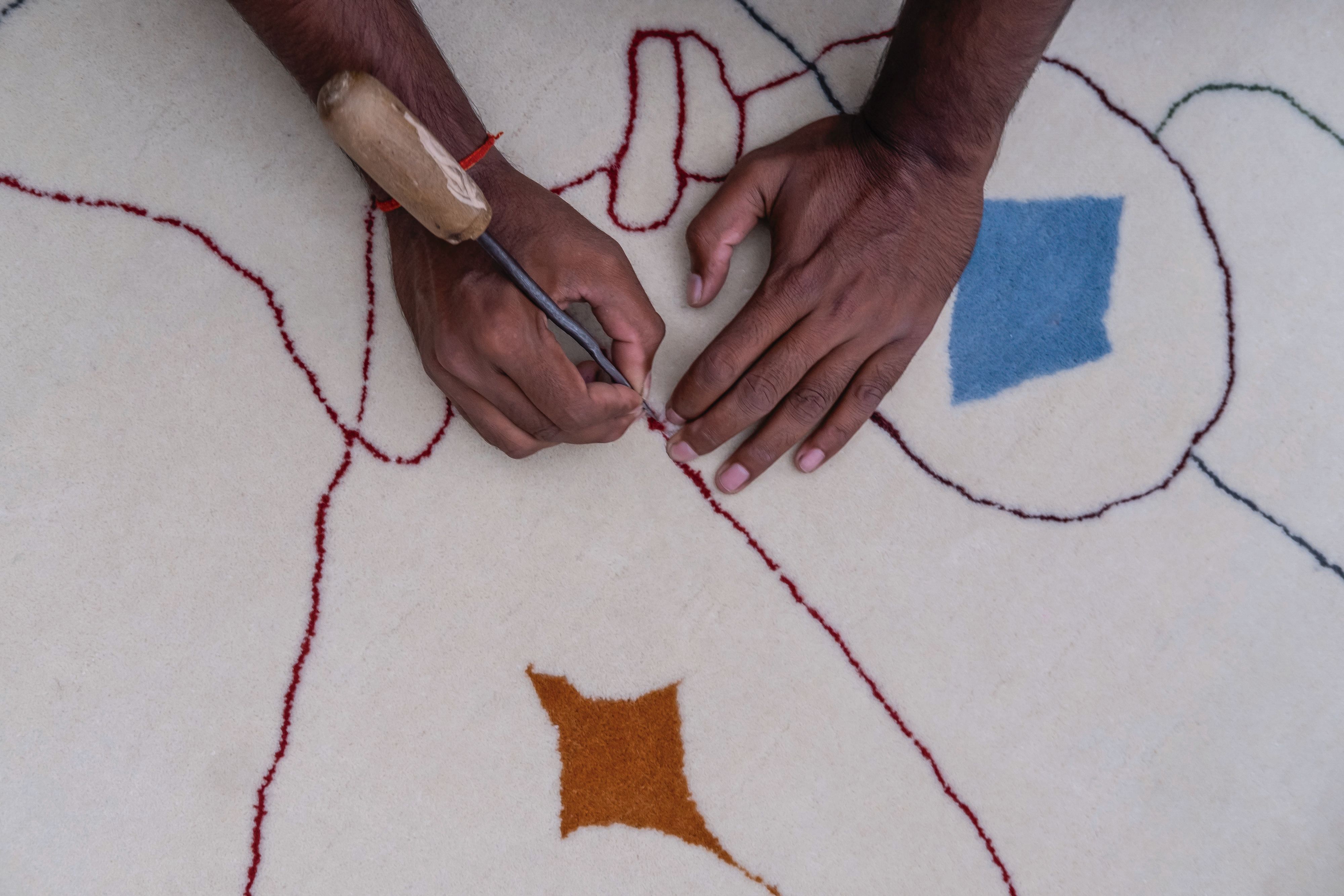 Detailaufnahme: Handwerkliche Fertigung des Nanimarquina Silhouette Outdoor Teppichs mit Werkzeug. Hochwertiger Outdoor Teppich.