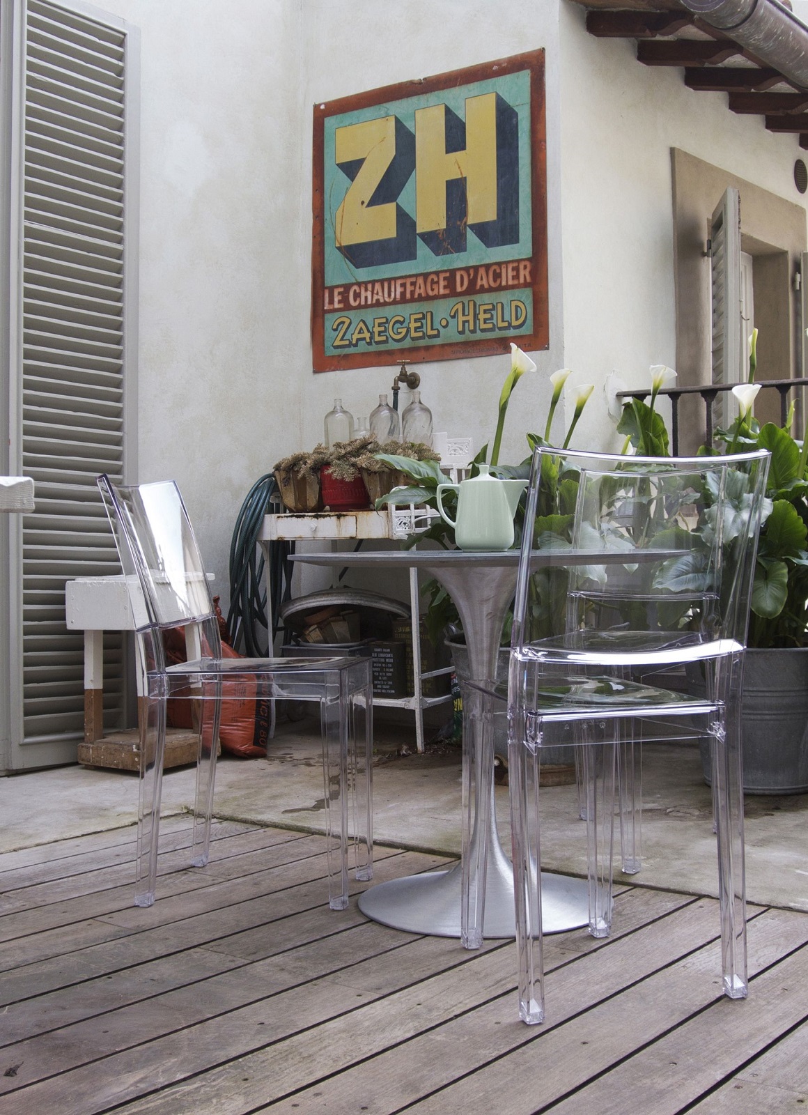 Zwei transparente La Marie Stühle von Kartell auf einer Holzterrasse, modernes Möbeldesign.