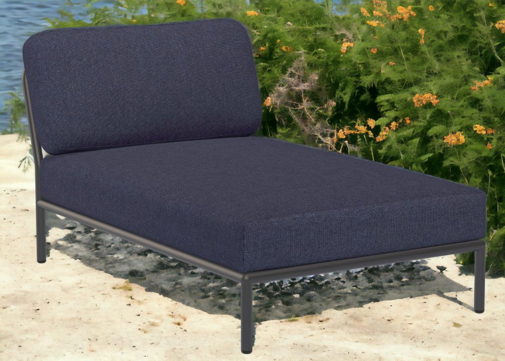 Houe Level Chaiselongue Outdoor Sessel in Blau mit schwarzem Rahmen vor Küstenkulisse.