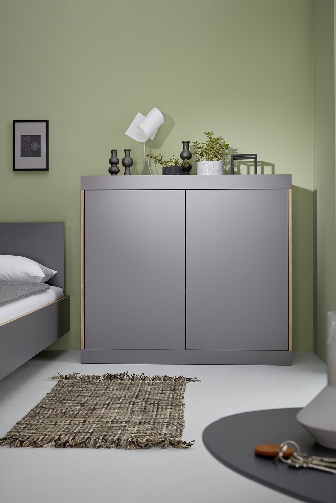 Graue Flai Kommode von Müller Möbelwerkstätten im Schlafzimmer mit Deko und Teppich.