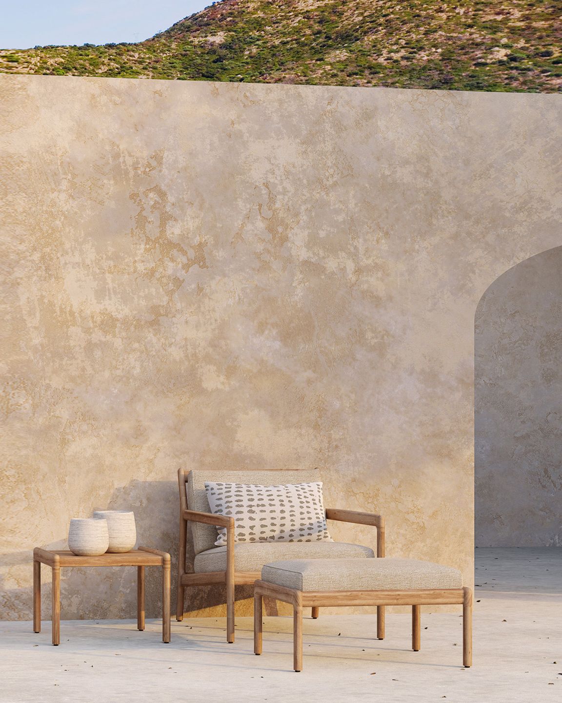 Ethnicraft Jack Outdoor Polsterhocker aus Teakholz mit Beistelltisch und Dekoration vor einer Wand.