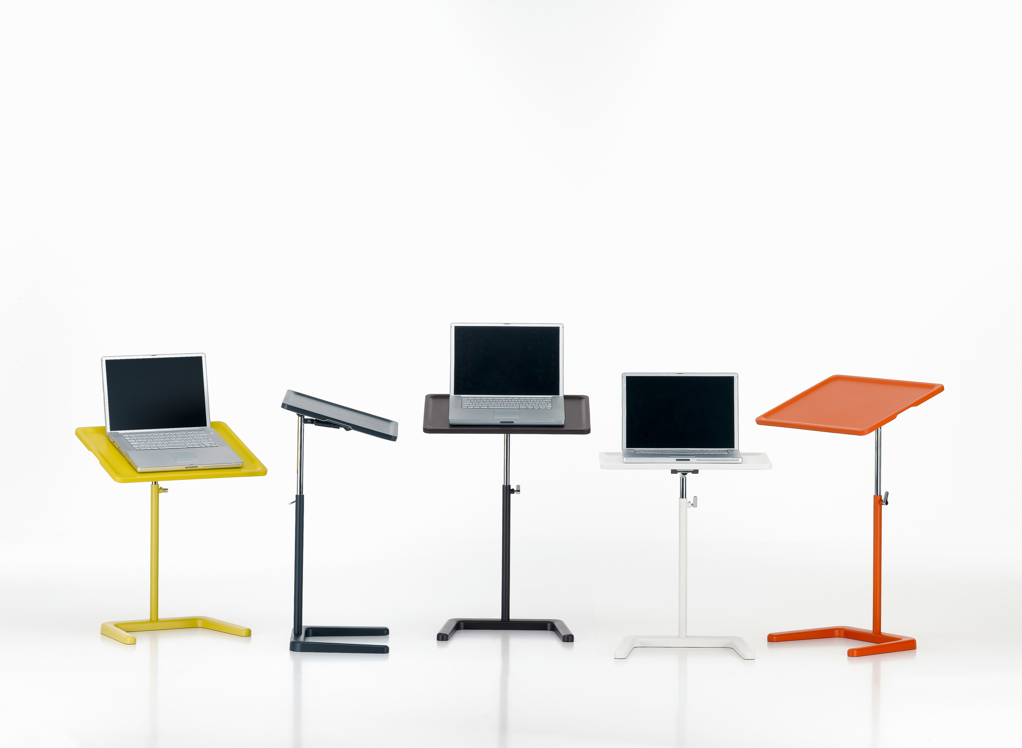 Verschiedene farbige Nes Table Beistelltische von Vitra, höhenverstellbar, mit Laptops darauf.