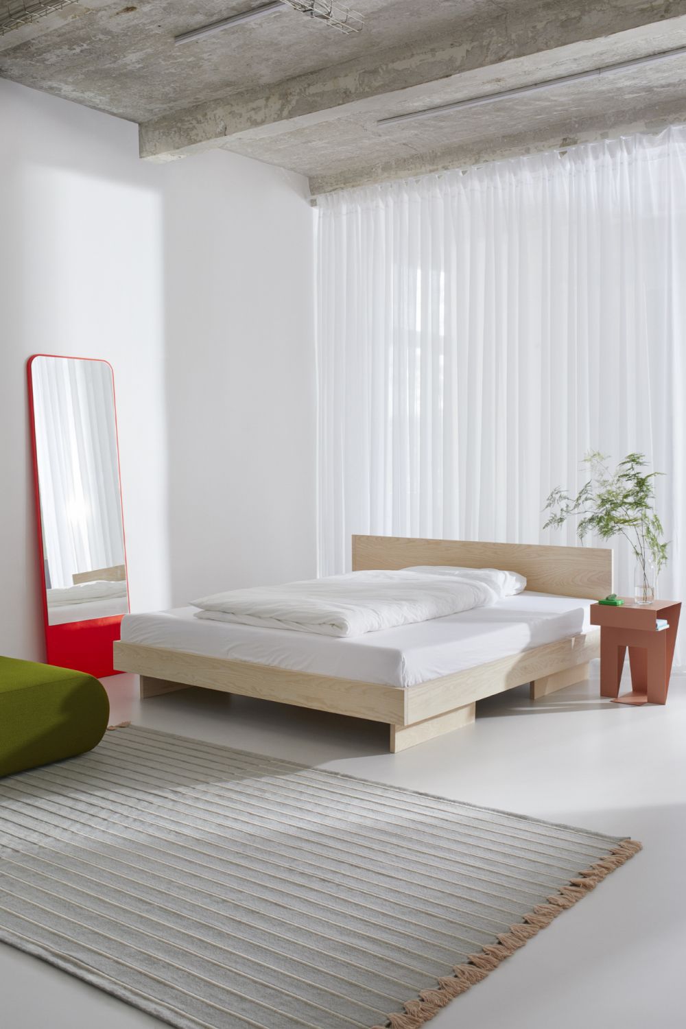 ZIANS Bett Large mit Kopfteil aus gewachster Eiche im minimalistischen Schlafzimmer mit Teppich und Spiegel.