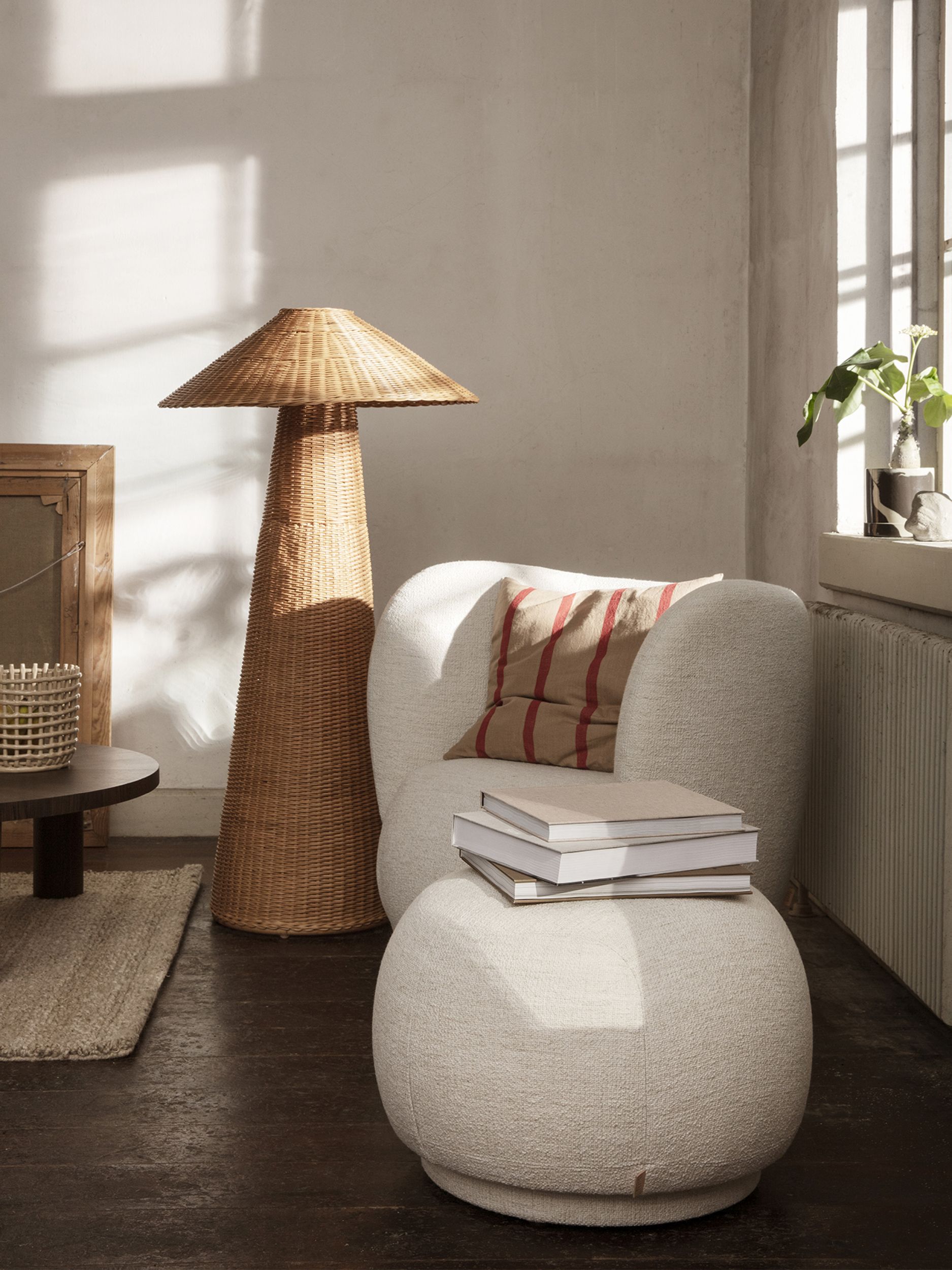 Beiger Rico Pouf von Ferm Living mit Büchern und Kissen in einem hellen Wohnzimmer.