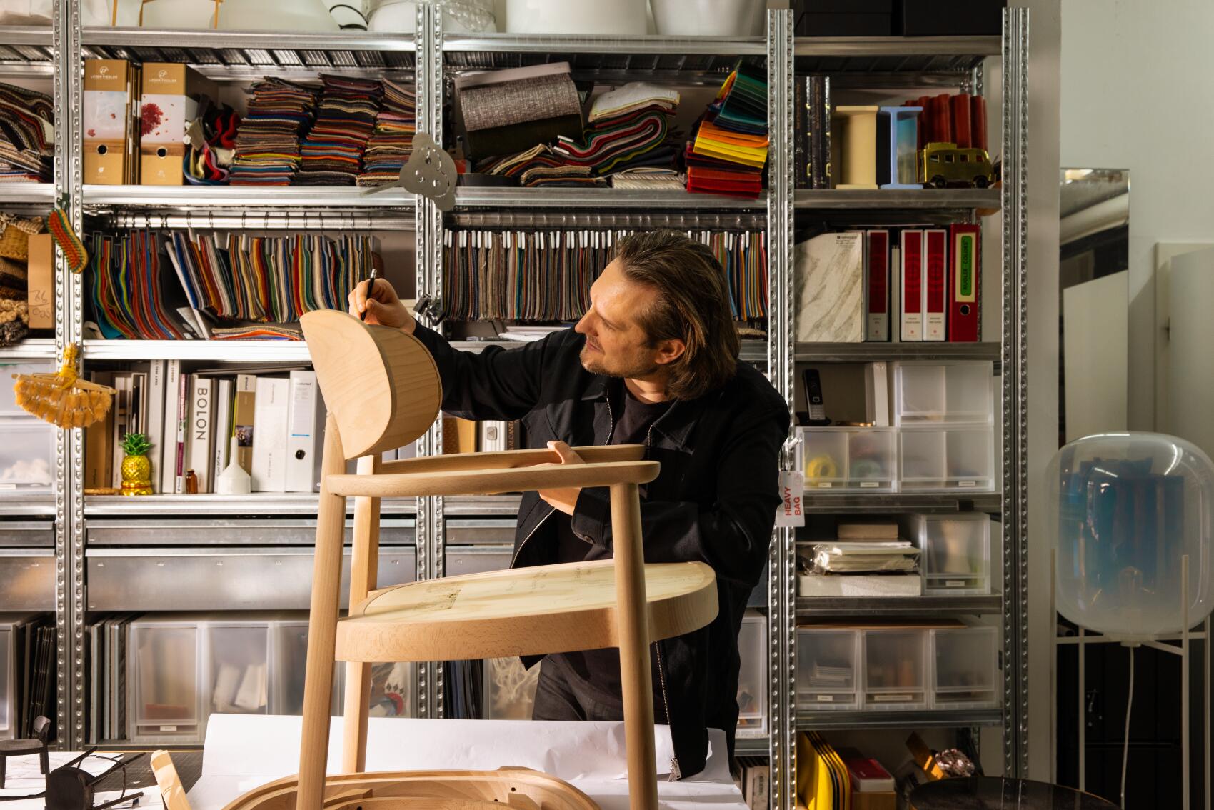 Mann arbeitet an einem hellen Holzsessel mit Armlehnen, möglicherweise ein Thonet Stuhl.