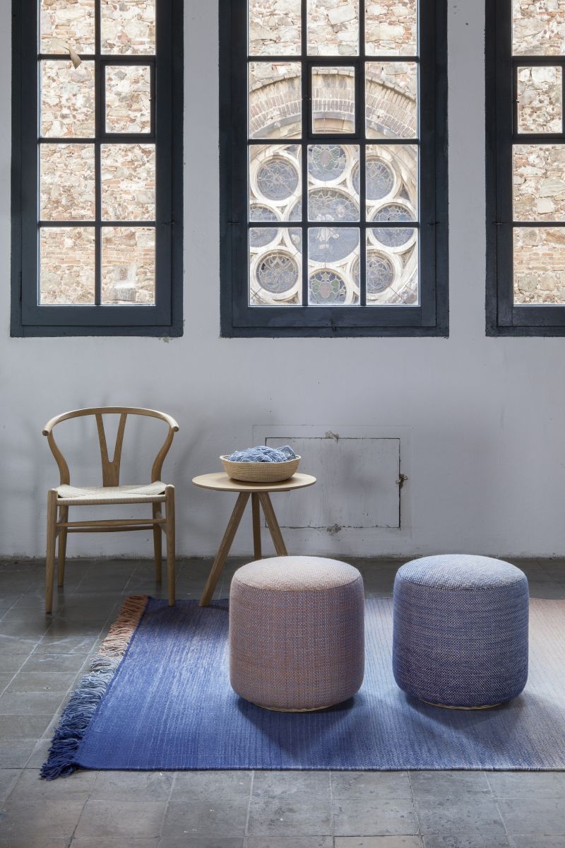 Zwei Nanimarquina Shade Pouf Hocker in Blau und Rosa auf einem blauen Teppich.