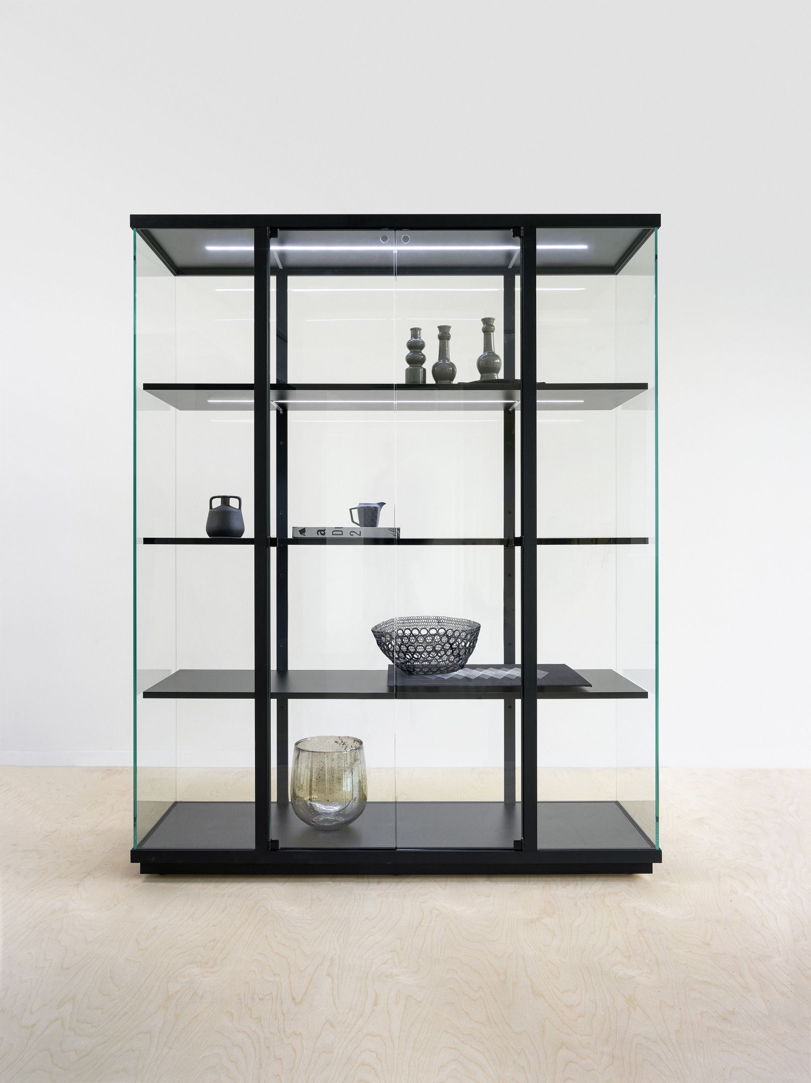 Schwarze Stolp Vitrine mit Glasfronten und LED-Beleuchtung, ideal für Wohnzimmer und Esszimmer.