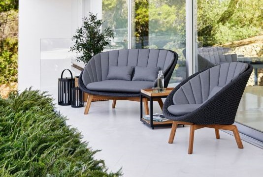 Graue Outdoor-Lounge-Gruppe mit Sofa und Sessel aus Rattan und Holz für Terrasse und Garten.