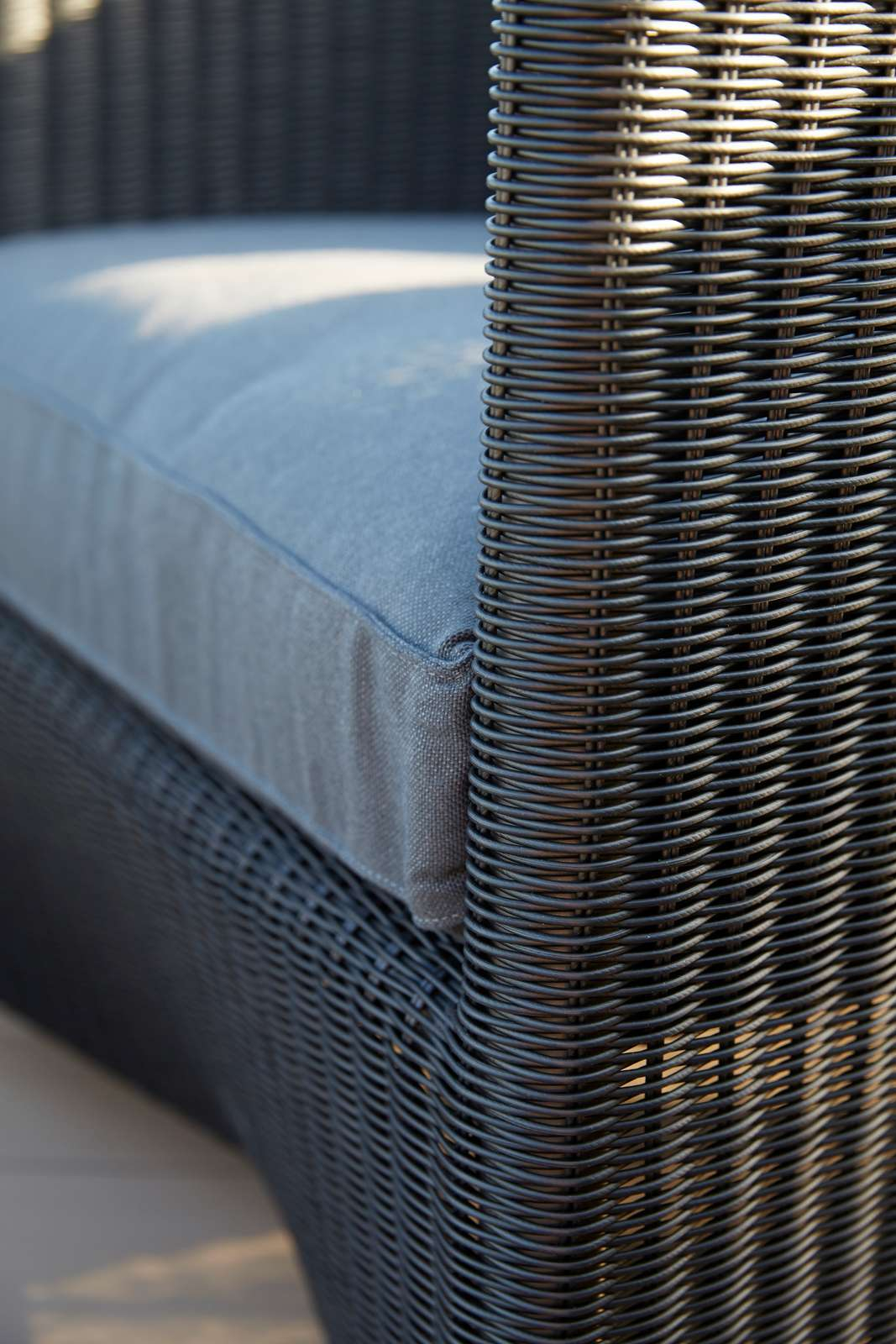 Detailaufnahme des Cane-Line Diamond Outdoor Sofas: Geflochtenes Design und graues Sitzkissen für den Garten.