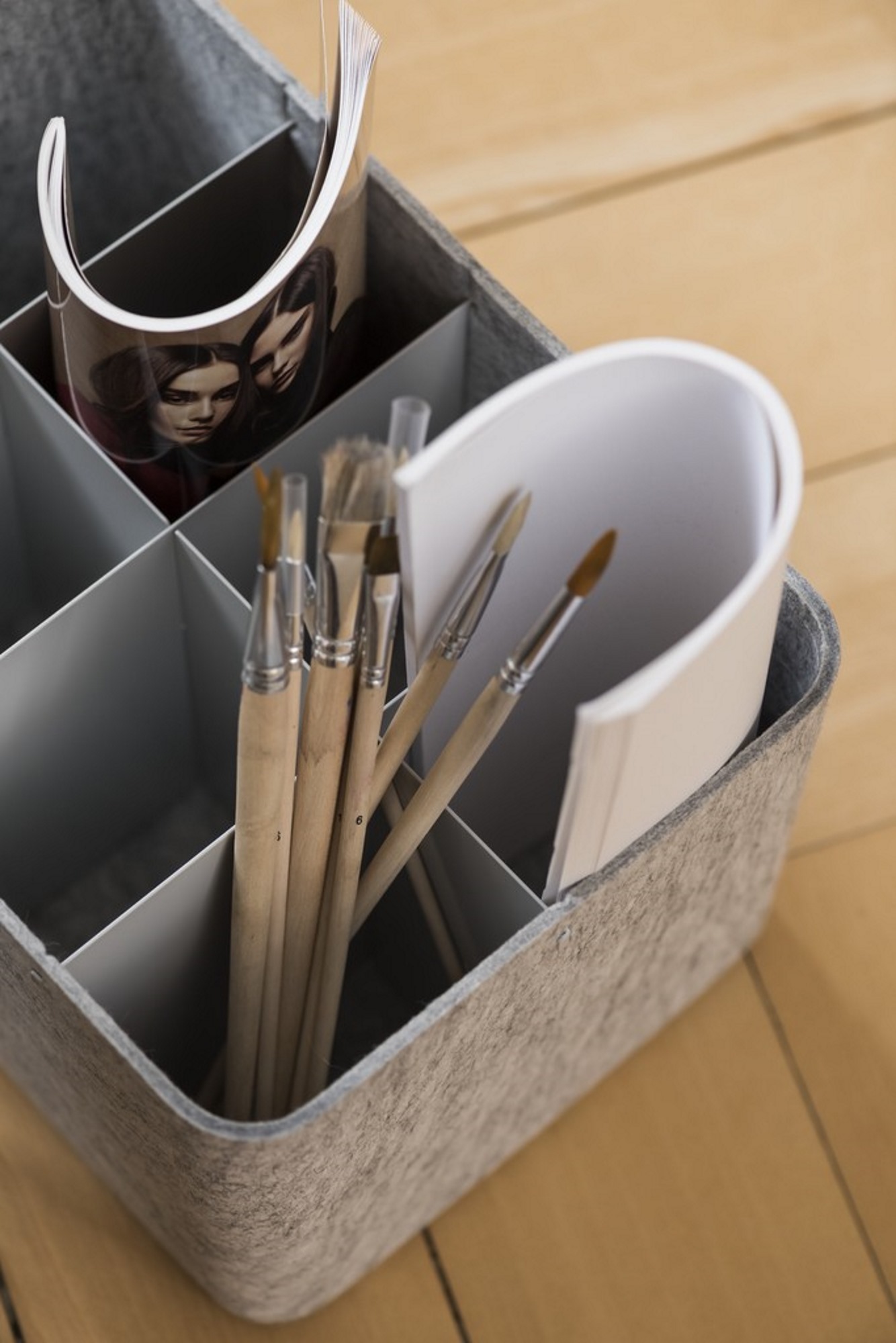 USM Haller Inos Box hoch, dunkelgrau, gefüllt mit Pinseln, Magazin und Papier, zur Aufbewahrung und Organisation.