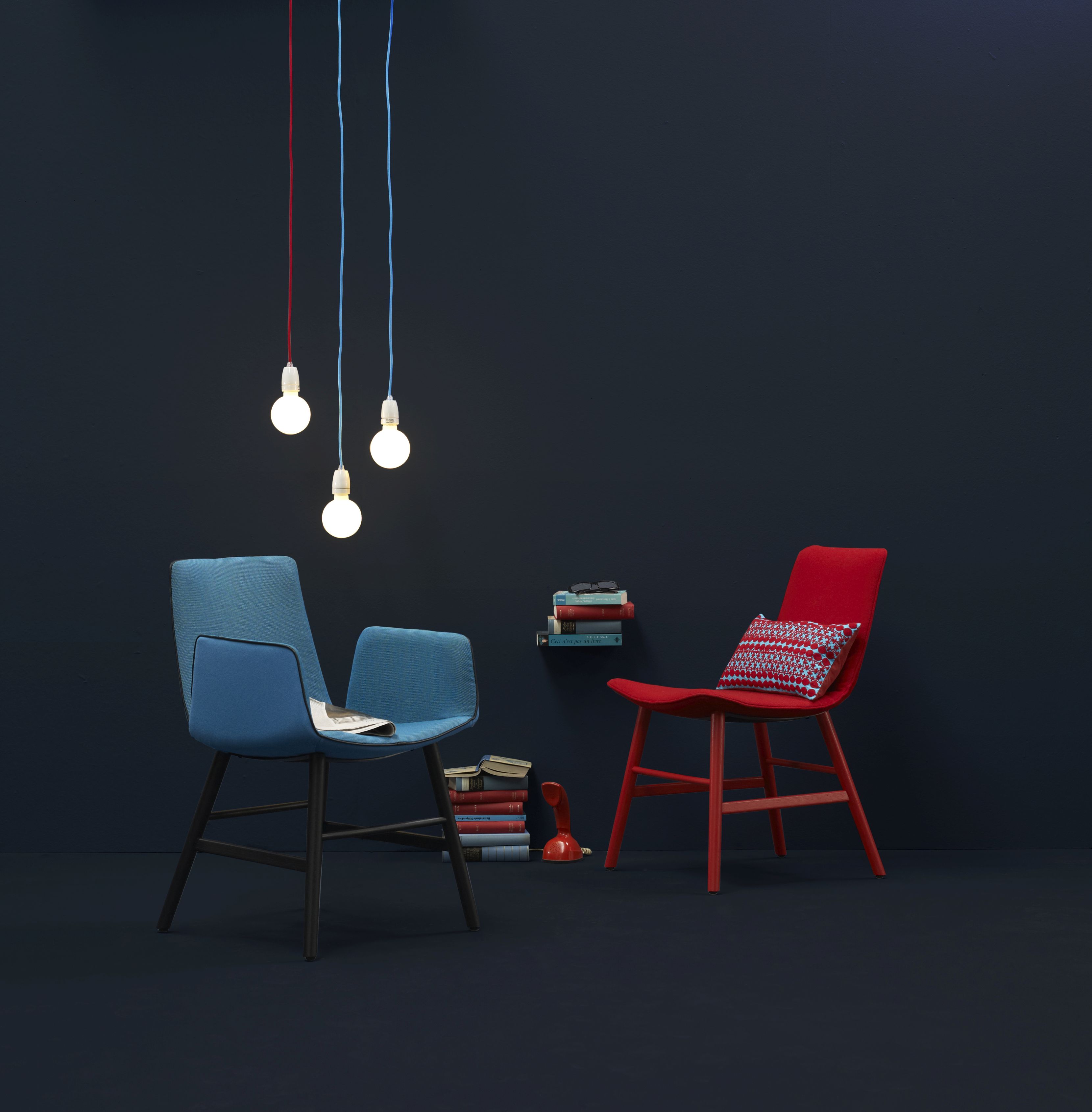 Blauer Amelie Armlehnstuhl von Freifrau Manufaktur mit hohen Armlehnen und roter Stuhl im Interieur.