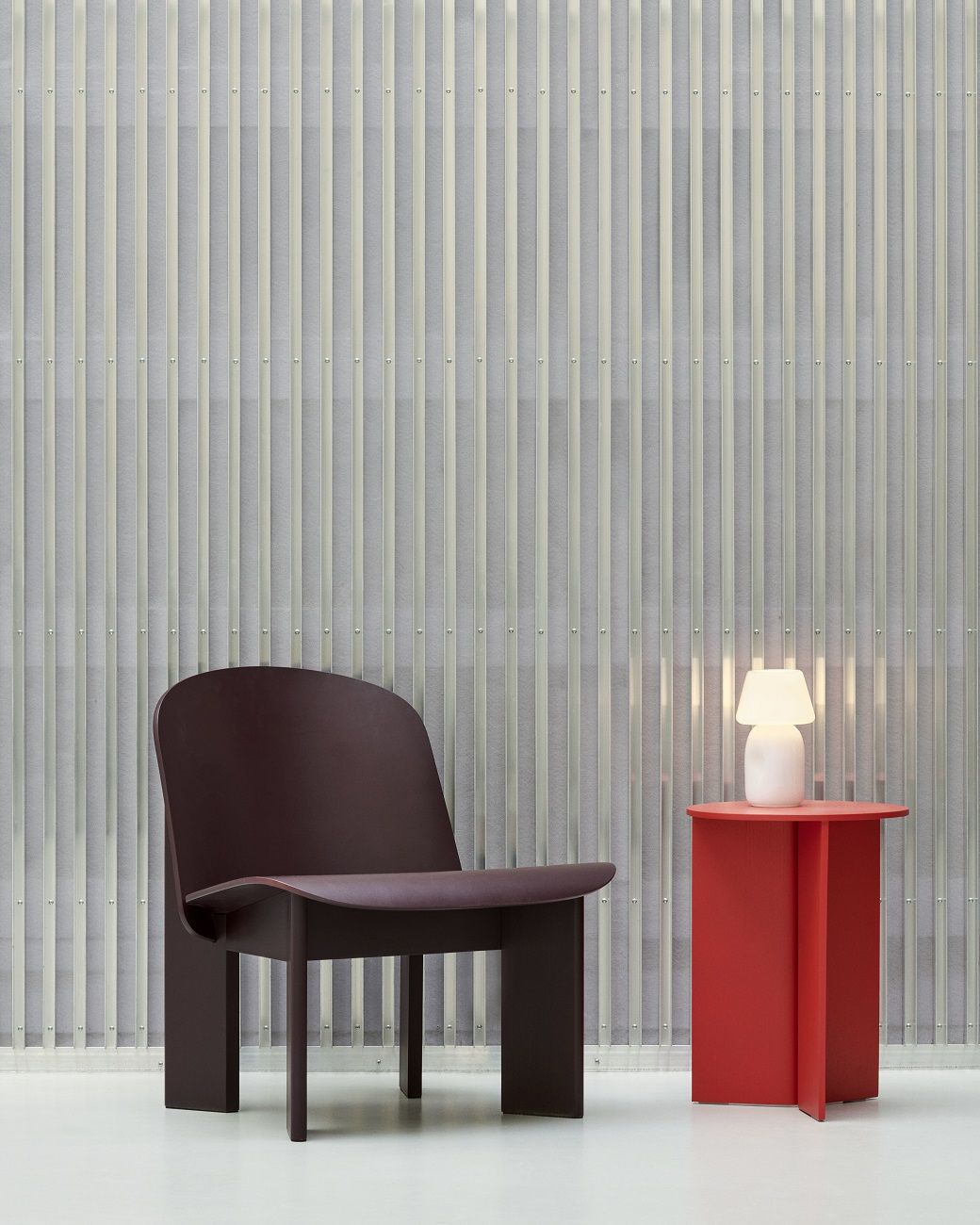 Dunkelbrauner Chisel Lounge Chair Sessel von Hay neben rotem Beistelltisch mit Lampe. Modernes Möbeldesign.
