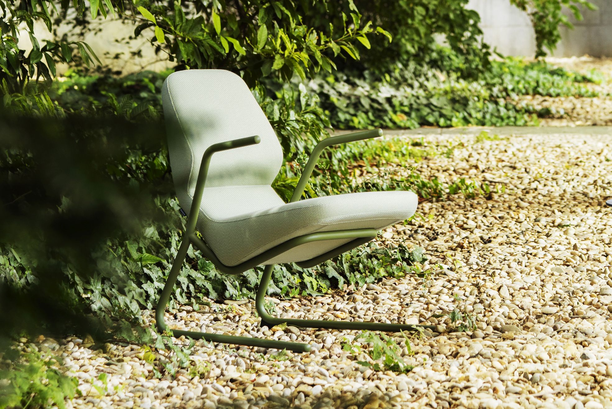 Heller Prostoria Oblique Sessel für drinnen und draußen, mit grünen Armlehnen und Gestell.